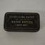 Small black oblong metal tin with white writing on lid.