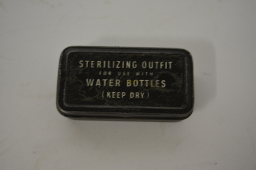 Small black oblong metal tin with white writing on lid.