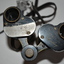 Small black binoculars - made of metal with black hard rubber over the top, metal eye protectors and leather strap. 