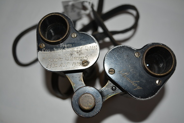 Small black binoculars - made of metal with black hard rubber over the top, metal eye protectors and leather strap. 