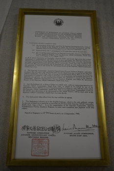 Gold coloured framed document with signatures and red stamp