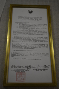 Gold coloured framed document with signatures and red stamp
