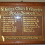 Carved timber frame and mounting with 16 names in gold coloured paint listed in two columns.