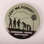 Circular badge with green background and black text and figures.  Six soldiers are silhouetted next to a tree.