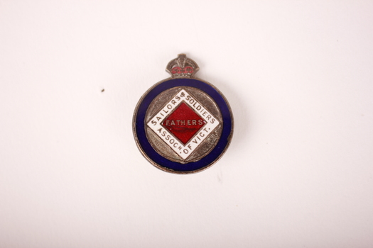 Round bronze and enamel badge badge with blue circular border enclosing a white and red diamond. Crown on top.