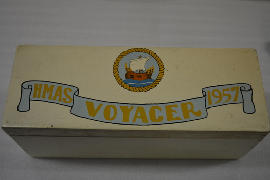 Cream painted wooden box with metal hinges.  There is an inscription and ship on the lid and autographs written in ink on the underside of the lid.   
