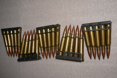 Five metal clips each containing five metal rounds of ammunition