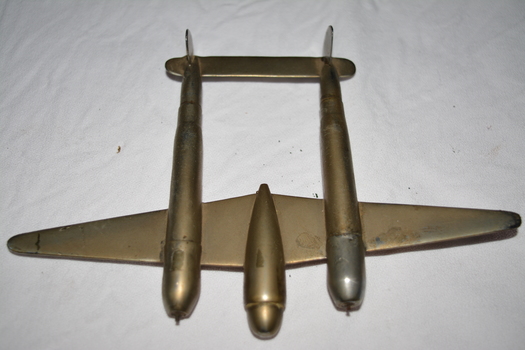 Silver/bronze coloured metal object in the shape of a model P38 plane made out of 303 shells