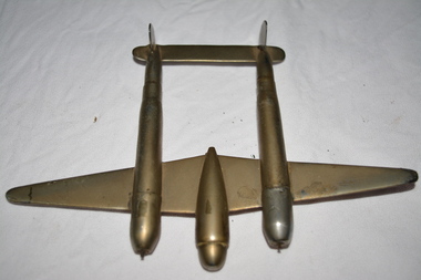 Silver/bronze coloured metal object in the shape of a model P38 plane made out of 303 shells