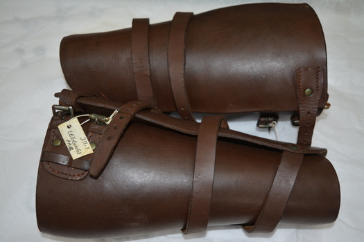 Pair of brown leather leggings. Has one long leather strap with buckle from ankle to calf & one short leather strap with buckle at top.