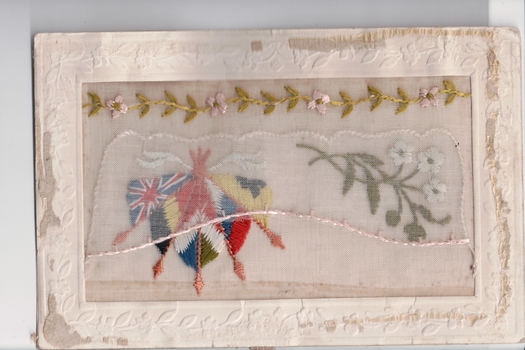 White rectangular postcard with embroidered flags, foliate and flowers.  Handwritten message on back.