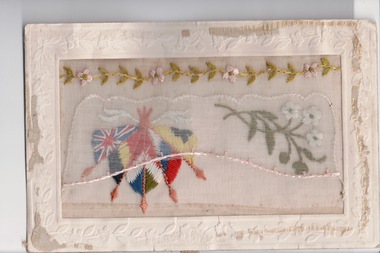 White rectangular postcard with embroidered flags, foliate and flowers.  Handwritten message on back.