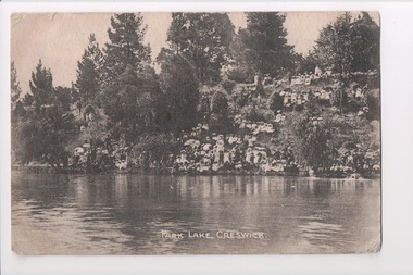 Black and white postcard of steep bank with trees leading down to wide river