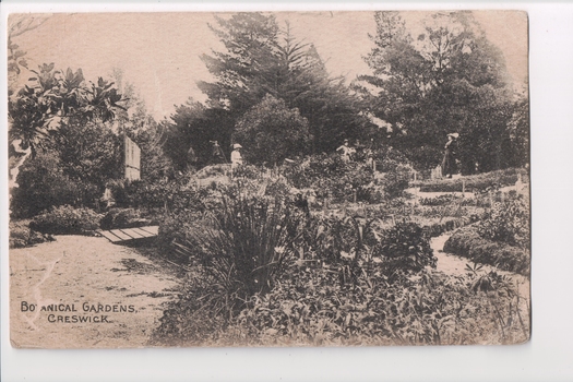 Black and white postcard of gardens with three women in background