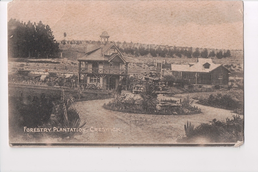 Postcard of two buildings with trees behind and circular driveway in front