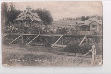 Black and white picture of two houses behind flower and vegetable garden.