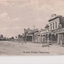 Black and white postcard of town buildings either side of road