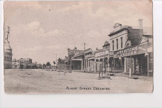 Black and white postcard of town buildings either side of road