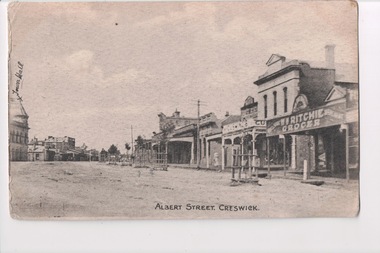 Black and white postcard of town buildings either side of road