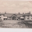 Black and white postcard of long  two story building 