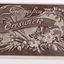 Postcard with a sepia coloured drawing of a banner and ornate cornucopian bouquet of flowers and wheat grains.  