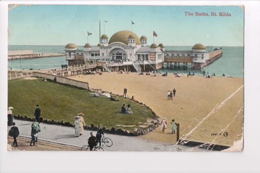 Colour postcard with a photograph of the beach and pier leading to building over water (St Kilda Baths) 