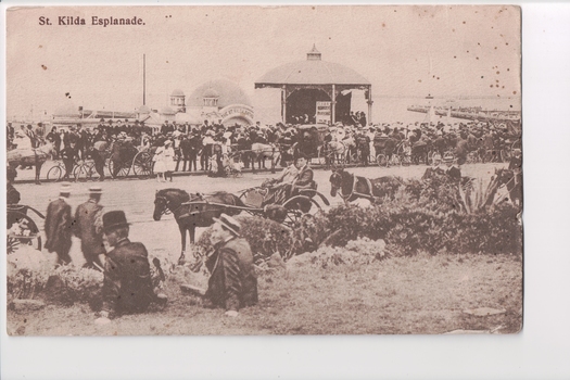 Postcard of sepia image of well dressed people lining roadway with horse and buggies in foreground