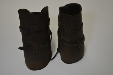 Dark brown leather curved to leg shape, with leather straps and buckles.