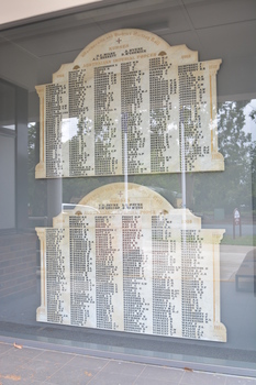 Irregular shaped marble honour roll with carved side columns and in between there are six columns of names in black