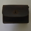 Brown leather pouch with front flap and two belt keepers on the back. Has large yellowing stitching.