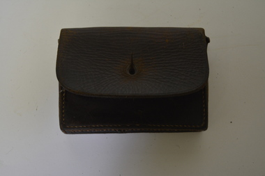 Brown leather pouch with front flap and two belt keepers on the back. Has large yellowing stitching.