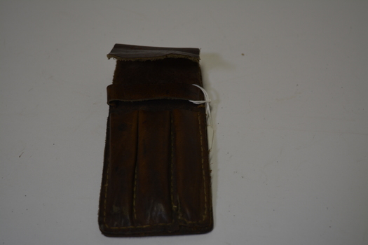 Home made tan leather pen case for three pens.  Has large yellowing stitching.
