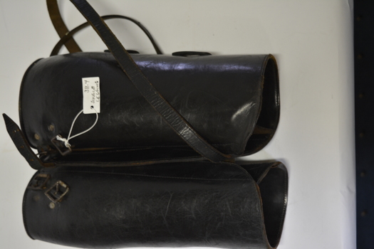 Pair black leather leggings.  Has long leather strap that winds around leg from calf to ankle.  Both leather straps have buckles.