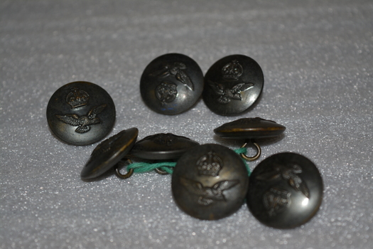 Round metal buttons for an Australian Air Force tunic with a carving of a crown at the top and an eagle underneath.