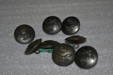 Round metal buttons for an Australian Air Force tunic with a carving of a crown at the top and an eagle underneath.