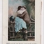 Man wearing straw boater hat and woman wearing green skirt sitting on a fence embracing one another