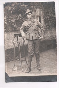 Black and white photograph of soldier wearing slouch hat leaning his right elbow on stand