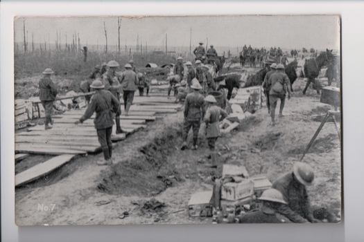 Large number of soldiers wearing tin hats constructing timber roadway
