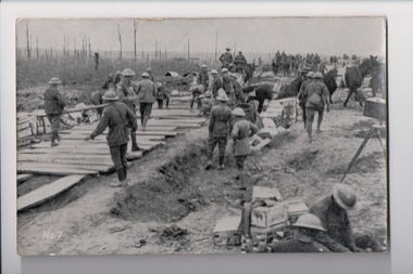 Large number of soldiers wearing tin hats constructing timber roadway
