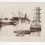 Ship docked alongside pier with barges in foreground