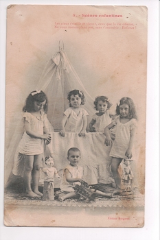 Four children standing two inside a cot and another child sitting on floor