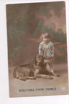Small child standing next to dog lying down with background of green trees