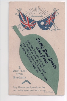 Postcard with rising sun and two flags above attached cutout in the shape of a gum leaf.
