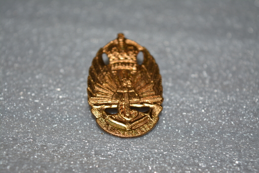 Gold badge with crown on top, rising sun in middle, an anchor at the bottom.