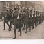 Postcard depicting image of armed soldiers marching in formation along street