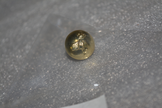 Small gold coloured metal button embossed with crown and map of Australia with loop fitting at rear.