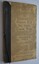 Book has black binding with black cord to bind it. Cover is a dirty cream colour with black writing. 