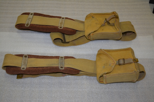 Two long canvas straps with felt shoulder padding, metal buckle and canvas pocket 