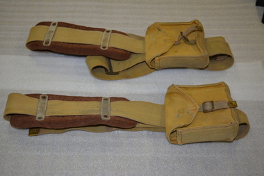 Two long canvas straps with felt shoulder padding, metal buckle and canvas pocket 