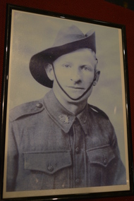 Black plastic frame containing photocopy of photograph of soldier wearing slouch hat.